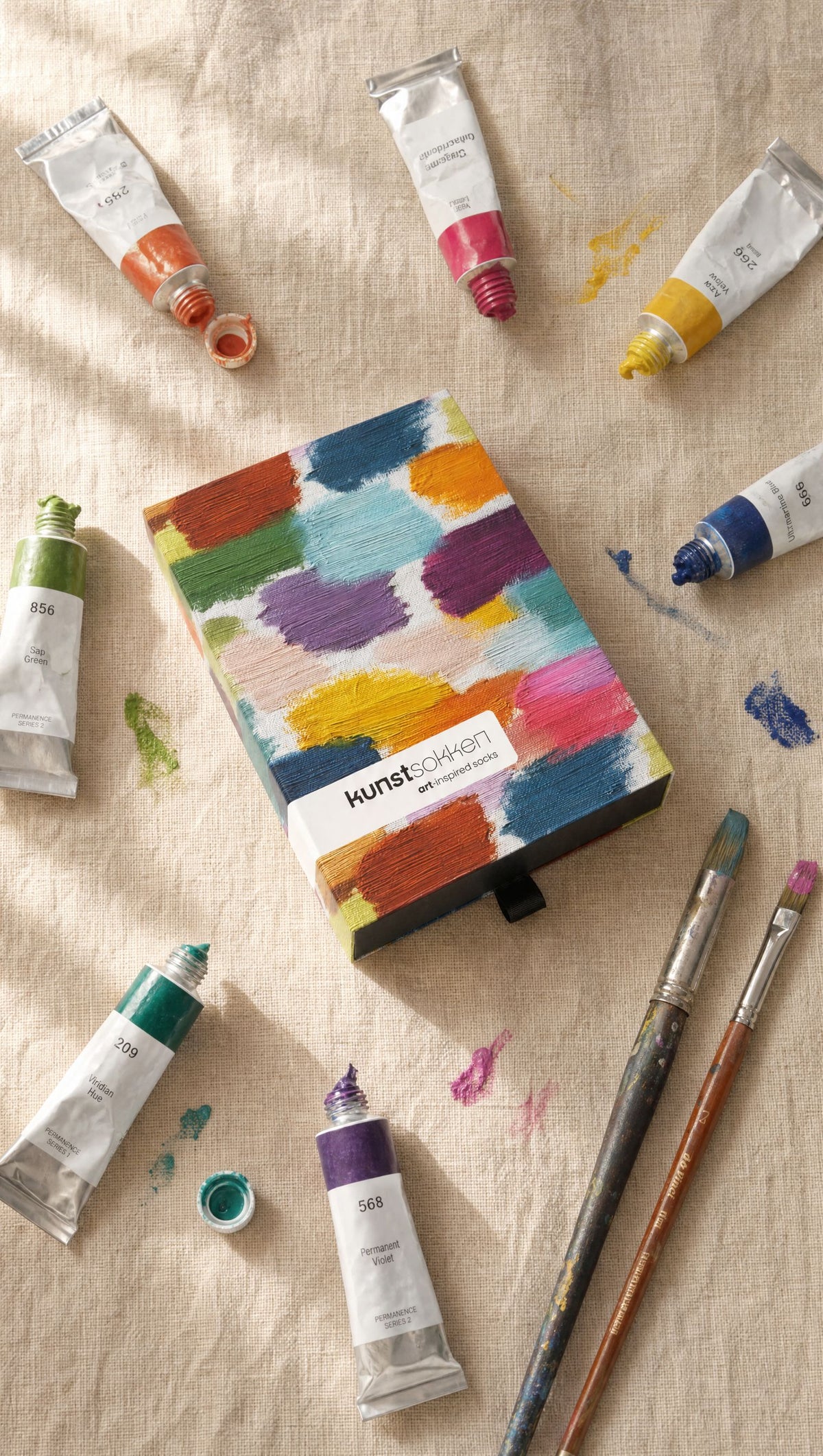 Kunstsokken cadeaudoos met penseelstreken op linnen, tussen tubes verf en penselen