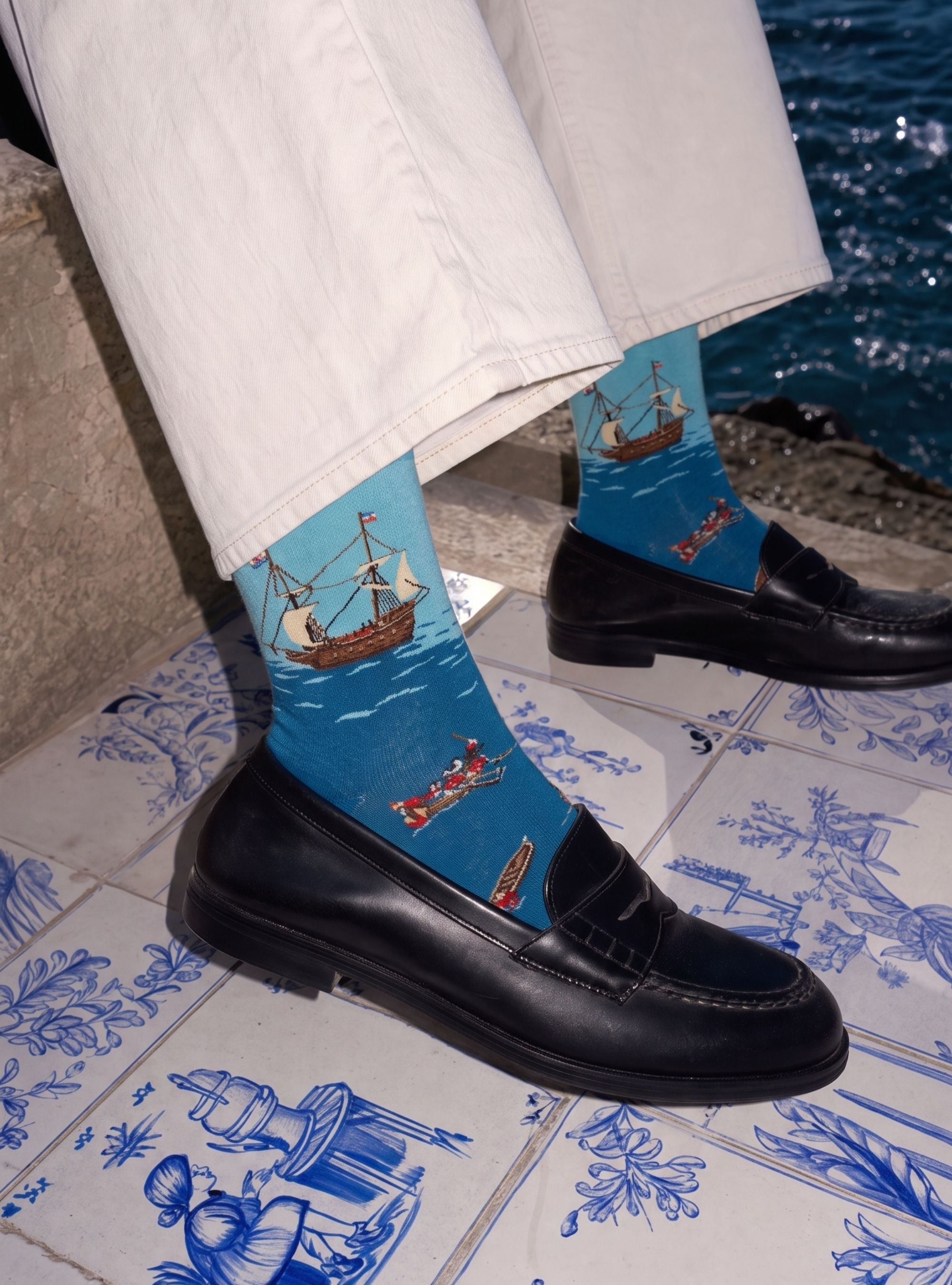 De Slag bij Gibraltar sokken gedragen bij zwarte loafers op blauwe tegels